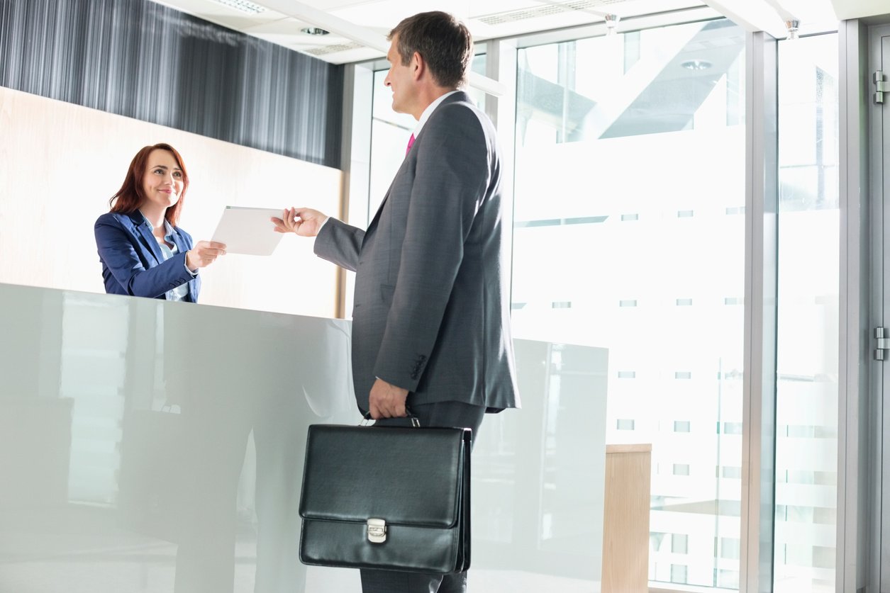 Businessman receiving document from receptionist in office